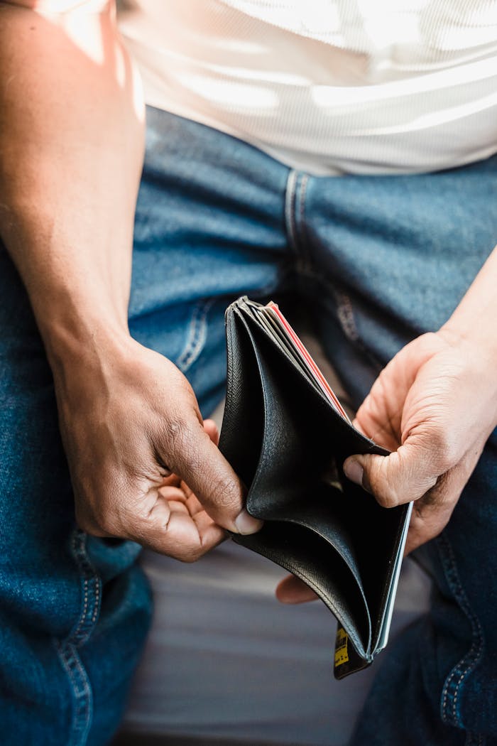 Close-up of a person holding an empty leather wallet, symbolizing financial struggle.